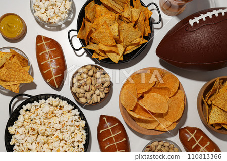 Popcorn and chips with a rugby ball on a light background Popcorn and chips with a rugby ball on a light background 110813366