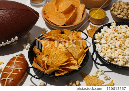 Popcorn and chips with a rugby ball on a light background Popcorn and chips with a rugby ball on a light background 110813367
