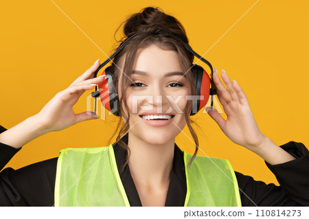 A young girl in a builder's uniform and headphones 110814273