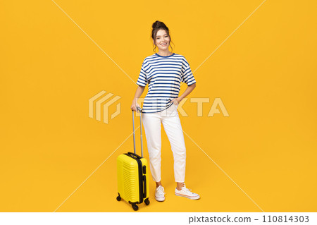 A young girl with a yellow suitcase on a yellow background 110814303