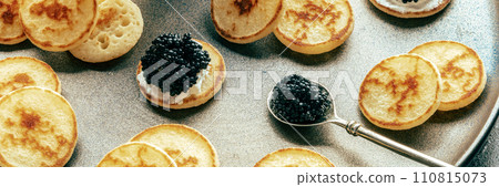 Blinis with black caviar and cream cheese panorama, on a festive dish 110815073