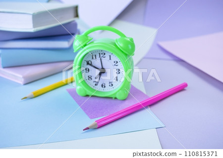Back to school, stationery, alarm clock, stack of books, paper and colored pencils on student's desk 110815371