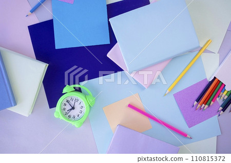 Back to school, stationery, alarm clock, stack of books, paper and colored pencils on student's desk, top view 110815372