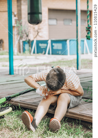 Child's leg injury. The child injured his knee when he fell off the scooter. The boy uses an antibacterial agent to treat the wound 110815429
