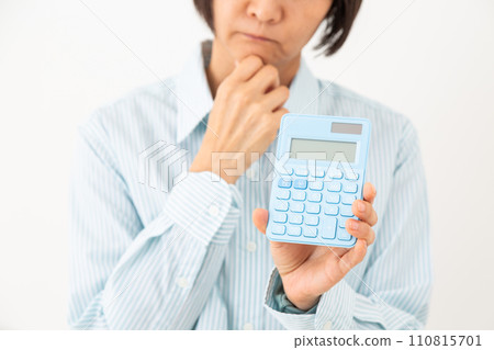 A middle-aged woman holding a black calculator and worrying A middle-aged woman holding a black calculator and worrying 110815701