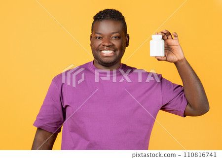 Cheerful black man showing jar of pills over yellow background Cheerful black man showing jar of pills over yellow background 110816741