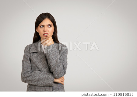 Woman in plaid blazer pondering, looking sideway at free space 110816835