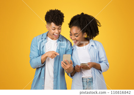 A young woman and man share a joyful moment looking at a smartphone together A young woman and man share a joyful moment looking at a smartphone together 110816842
