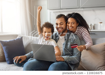 Happy Black Family With Laptop And Credit Card Making Shopping At Home Happy Black Family With Laptop And Credit Card Making Shopping At Home 110816875