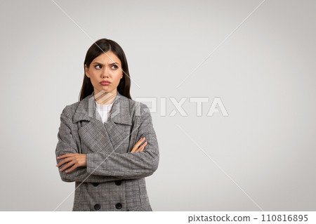Skeptical young lady in tweed jacket, arms crossed 110816895