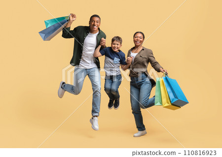Overjoyed african american family jumping with purchases Overjoyed african american family jumping with purchases 110816923