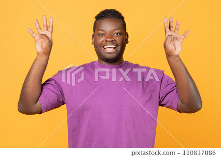 African American man raising hands showing number eight, yellow background 110817086