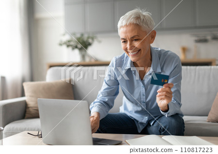 senior lady smiling shopping on laptop holding credit card indoor 110817223