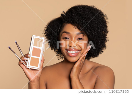 Joyful woman showcasing makeup palette and brushes Joyful woman showcasing makeup palette and brushes 110817365