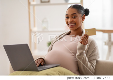 Positive black lady expecting baby, using laptop and credit card Positive black lady expecting baby, using laptop and credit card 110817382