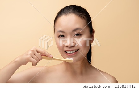 Cheerful millennial chinese woman with perfect smile, brushing teeth with toothbrush Cheerful millennial chinese woman with perfect smile, brushing teeth with toothbrush 110817412