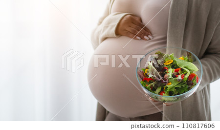 Cropped of black lady expectant holding fresh vegetable salad Cropped of black lady expectant holding fresh vegetable salad 110817606