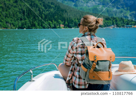 traveller woman enjoying beautiful view of turquois Lake and mountains sitting on sailing paddleboat traveller woman enjoying beautiful view of turquois Lake and mountains sitting on sailing paddleboat 110817766