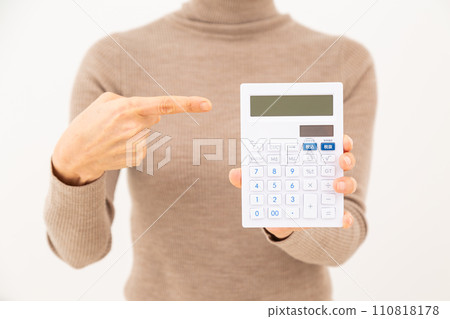 Middle-aged woman pointing at a white calculator Middle-aged woman pointing at a white calculator 110818178