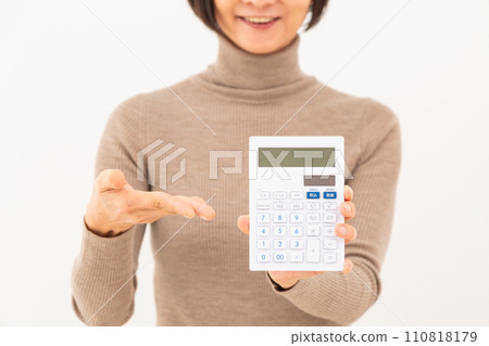 A middle-aged woman smiling while holding a white calculator A middle-aged woman smiling while holding a white calculator 110818179