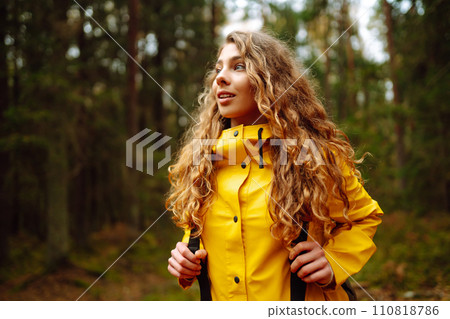 Traveler woman in yellow coat explores, walks through wild forest in nature. Vacation travel concept 110818786