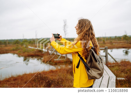 Tourist travels in nature, photographs landscapes in swamps using mobile phone. Active lifestyle. 110818898