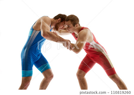 Young skilled wrestlers in blue and red uniform hand fighting in neutral position on their feet against white studio background. Young skilled wrestlers in blue and red uniform hand fighting in neutral position on their feet against white studio background. 110819260