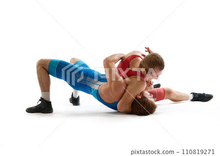 Greco-Roman, freestyle wrestling. Two sportsman, fighting in red and blue uniform in action against white studio background. 110819271