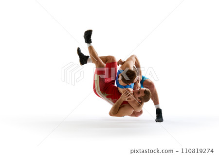 Two strong wrestlers in blue and red wrestling uniform fighting and making hip throw in motion against white studio background. Two strong wrestlers in blue and red wrestling uniform fighting and making hip throw in motion against white studio background. 110819274
