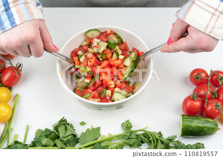 Vegetable salad seasoned with oil is mixed with spoons. 110819557