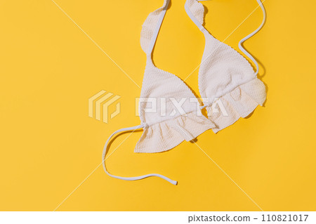 White swimsuit top on a yellow background 110821017