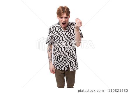 a young indignant guy with red hair and a tattoo on his arms is dressed in a short-sleeved shirt a young indignant guy with red hair and a tattoo on his arms is dressed in a short-sleeved shirt 110821380