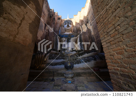 The buddha in Wat Si Chum in Sukhothai Historical Park, pagoda stupa, Sukhothai, Thailand. Thai buddhist temple architecture. Tourist attraction. The buddha in Wat Si Chum in Sukhothai Historical Park, pagoda stupa, Sukhothai, Thailand. Thai buddhist temple architecture. Tourist attraction. 110821743