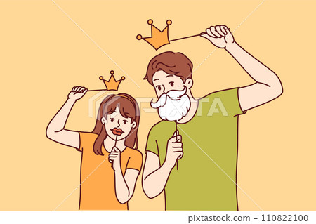 Funny family father and daughter are having fun trying on fake mustaches and crown from photo zone Funny family father and daughter are having fun trying on fake mustaches and crown from photo zone 110822100