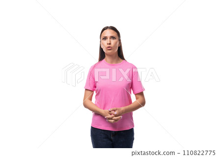 young slim european woman with black straight hair is dressed in a pink t-shirt on a studio young slim european woman with black straight hair is dressed in a pink t-shirt on a studio 110822775