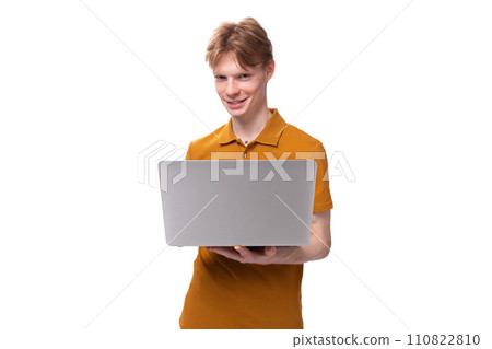 a young guy with short red hair dressed in a summer T-shirt uses a laptop computer 110822810