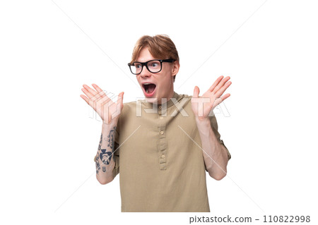 young redhead guy in glasses and a brown shirt is surprised on a white background 110822998