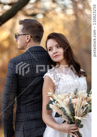 beautiful sensual bride in white wedding dress and groom standing outdoor on natural background beautiful sensual bride in white wedding dress and groom standing outdoor on natural background 110823258