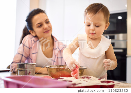 mother and little baby girl preparing the dough in the kitchen, bake cookies. happy time together 110823280