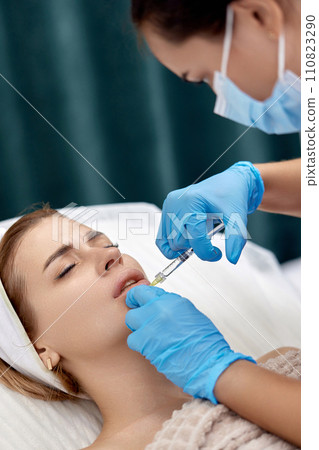 beautician makes injections to enlarge the lips of beautiful woman. procedure lip augmentation 110823290
