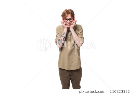handsome young red-haired man in a beige shirt wears eyeglasses on a white background 110823532