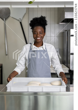 African american young woman preparing pizza in the kitchen 110823744