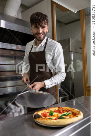 Dark-haired young man cooking pizza in pizzeria 110823753