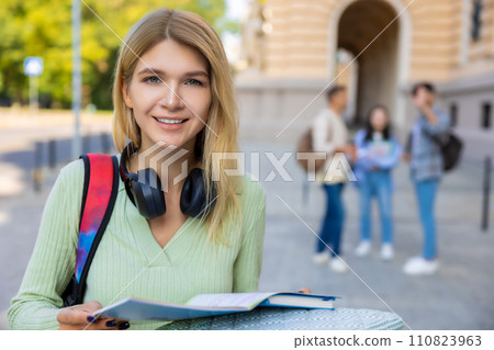 Female student with blonde hair reading book before classes or exam. 110823963