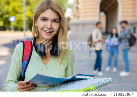 Woman student with books preparing for classes posing outdoor near college. 110823964