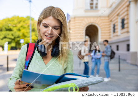 Woman student with books preparing for classes posing outdoor near college. Woman student with books preparing for classes posing outdoor near college. 110823966