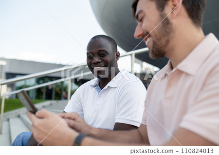 Two friends watching something on the phone and smiling 110824013