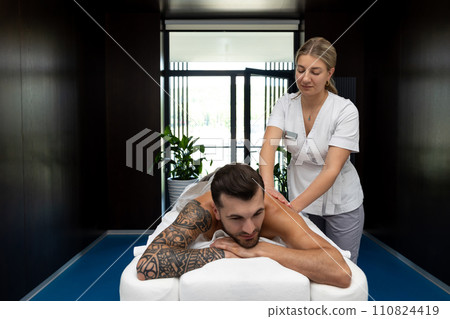 Man having back massage session and looking contented Man having back massage session and looking contented 110824419