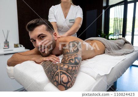 Young man with a big tattoo having back massage session in a salon 110824423