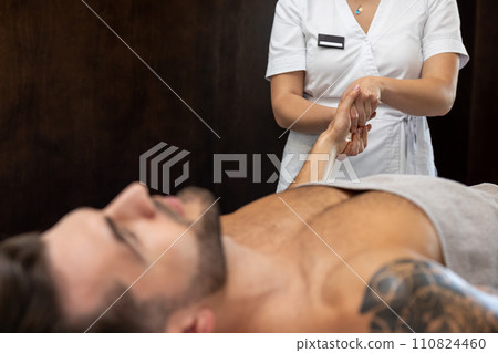 Young man lying on a couch and having procedures in a beauty salon Young man lying on a couch and having procedures in a beauty salon 110824460